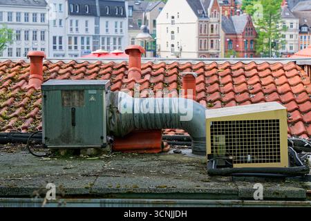 Auf einem flachen Betondach stehen ein Metallgehäuse mit Kanalkanal und ein Kunststoffeinlass mit Gitter. Saubere HLK-Details für Industrie-, Technik- und Anlagenbau Stockfoto