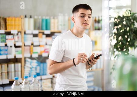 Ein junger Kerl, der in der Apotheke telefoniert Stockfoto