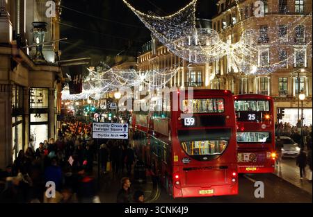 LONDON, GROSSBRITANNIEN. 17. DEZEMBER 2016. Menschenmassen und Doppeldeckerbusse bewegen sich unter glitzernden Weihnachtslichtern auf der Regent Street in der Nähe des Piccadilly Circus. Stockfoto