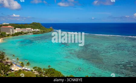 Atemberaubender Blick aus der Luft auf Tumon Bay, Guam, mit türkisfarbenem Meer, Korallenriffen und Luxusresorts entlang des weißen Sandstrands. Stockfoto