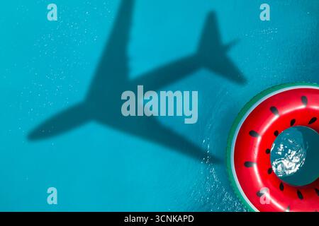 Aufblasbarer Ring schwimmend im Swimmingpool, Blick von oben. Fliegendes Flugzeug wirft Schatten auf Wasser Stockfoto