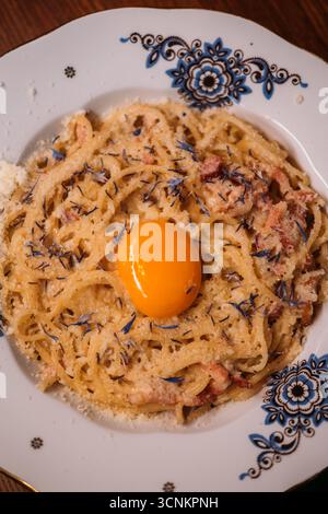 Nudeln serviert. Traditionelles italienisches Gericht. Appetitliche Nudeln mit Eigelb auf Teller. Leckeres Carbonara-Rezept mit geriebenem Käse. Stockfoto
