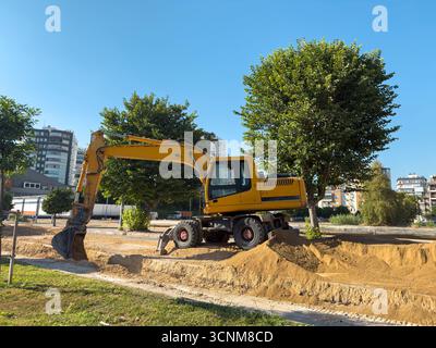 Gelber Bagger, der auf einer Sandbaustelle unter blauem Himmel arbeitet Stockfoto