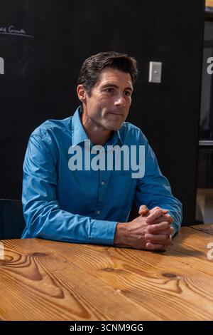 Mann, der am Tisch im Besprechungsraum sitzt, Hände an der Tafel festklemmt Stockfoto