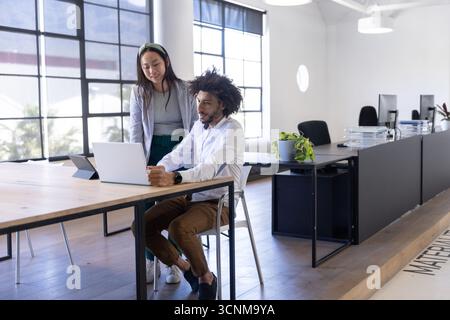 Verschiedene Kollegen arbeiten am Laptop am Holztisch im Büro mit Tablet zusammen Stockfoto