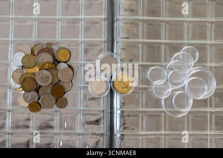Gemischte Weltmünzen auf Plastikmünzalbum Seite mit eingekapselten Münzen auf Albumseite Stockfoto