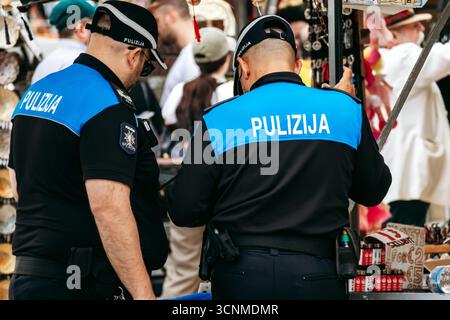 Marsaxlokk, Malta - 13. April 2025: Zwei maltesische Polizeibeamte in Uniformen mit Pulizija-Insignia patrouillieren auf dem geschäftigen Sonntagsmarkt im Fischi Stockfoto