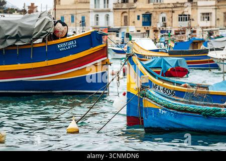 Marsaxlokk, Malta - 13. April 2025: Traditionelle, farbenfrohe maltesische Fischerboote, genannt Luzzu, mit leuchtend blauen, gelben und roten Details, die in der verankert sind Stockfoto
