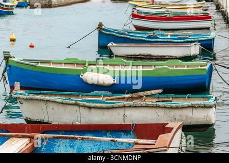Marsaxlokk, Malta - 13. April 2025: Traditionelle, farbenfrohe maltesische Fischerboote, genannt Luzzu, mit leuchtend blauen, gelben und roten Details, die in der verankert sind Stockfoto