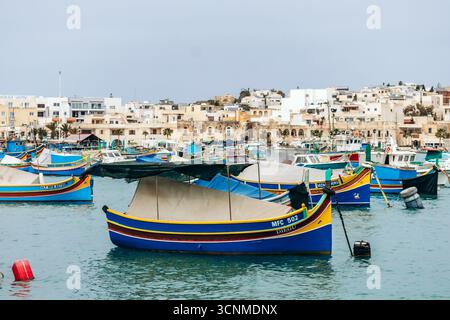 Marsaxlokk, Malta - 13. April 2025: Traditionelle, farbenfrohe maltesische Fischerboote, genannt Luzzu, mit leuchtend blauen, gelben und roten Details, die in der verankert sind Stockfoto