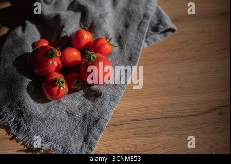 Lebendige und frische rote, saftige Tomaten auf einem bezaubernden Hintergrund mit blauem Tuch Stockfoto