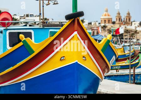 Marsaxlokk, Malta - 13. April 2025: Traditionelle, farbenfrohe maltesische Fischerboote, genannt Luzzu, mit leuchtend blauen, gelben und roten Details, die in der verankert sind Stockfoto