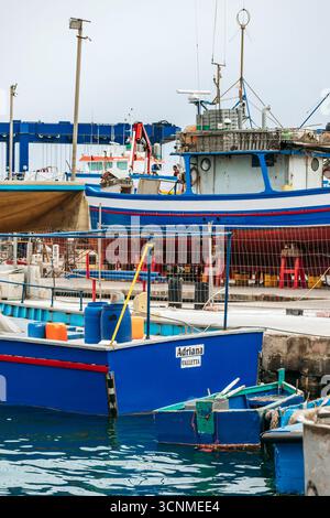 Marsaxlokk, Malta - 13. April 2025: Traditionelle, farbenfrohe maltesische Fischerboote, genannt Luzzu, mit leuchtend blauen, gelben und roten Details, die in der verankert sind Stockfoto