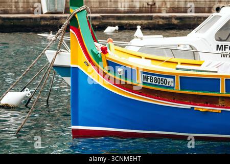 Marsaxlokk, Malta - 13. April 2025: Traditionelle, farbenfrohe maltesische Fischerboote, genannt Luzzu, mit leuchtend blauen, gelben und roten Details, die in der verankert sind Stockfoto