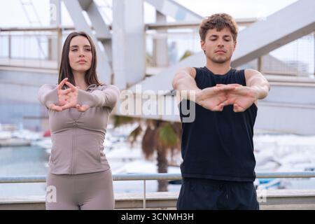 Junges Paar, das sich gemeinsam im Freien in städtischer Umgebung ausdehnt Stockfoto