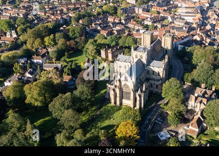 Luftaufnahme der Kathedrale von Ripon in Ripon, North Yorkshire, Großbritannien, aufgenommen bei klarem Spätsommerwetter mit hellblauem Himmel und warmem Sonnenlicht, das die beeindruckende gotische Architektur der Kathedrale unterstreicht. Das Bild zeigt die elegante frühe englische Westfront mit ihren Doppeltürmen, komplizierten Mauerwerken und bogenförmigen Fenstern, umgeben von den historischen Straßen der Stadt, nahe gelegenen Gebäuden, Dächern und Grünflächen einschließlich Parks und offenen Bereichen. Dieser Blick über der Drohne fängt die zentrale Position der Kathedrale in der kompakten mittelalterlichen Stadt ein und betont ihre Rolle als wichtiges Wahrzeichen des Kulturerbes Stockfoto