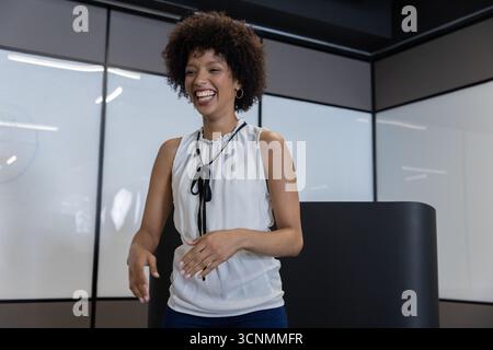 afroamerikanerin, die im Büro spricht, mit Glaswänden, Podiumbeleuchtung, Whiteboard-Blendung Stockfoto