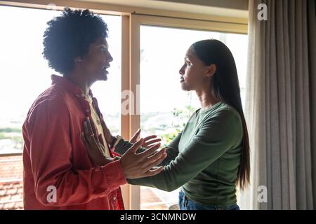 Diverse Paare stehen im Wohnzimmer mit Blick auf die Glasschiebetür mit Pflanzen, Geländer Stockfoto