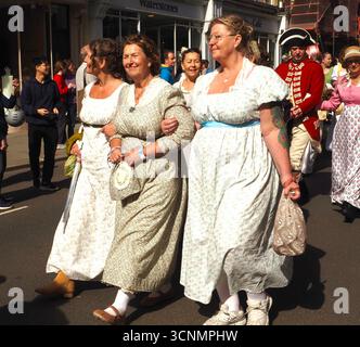 Menschen, die in Regentschaftskostümen gekleidet sind, nehmen an einer Promenade durch die Straßen von Bath bei der Jane Austen Festival Parade 2025 teil. Stockfoto