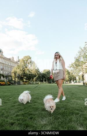 Frau, die zwei Pommern im Park herumläuft Stockfoto
