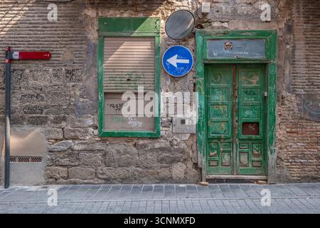Alte Verwitterte Steinmauer Mit Grüner Holztür. Urbane verfallene Fassade, Vintage-Architektur, traditionelles mediterranes Gebäude, veraltetes Mauerwerk Stockfoto