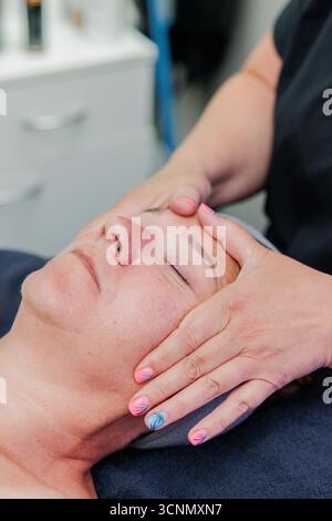 Frau, die eine entspannende Gesichtsmassage von einem Kosmetiker erhält Stockfoto