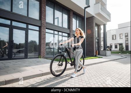 Kaukasierin in Sportbekleidung, die mit dem Fahrrad auf der Straße läuft Stockfoto