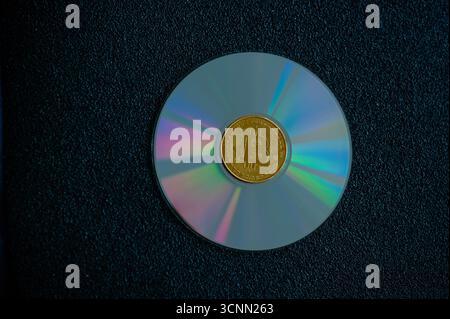 Goldene Bitcoin-Münze auf einer CD, die digitale Währung, Datenspeicherung und moderne Finanztechnologie symbolisiert Stockfoto
