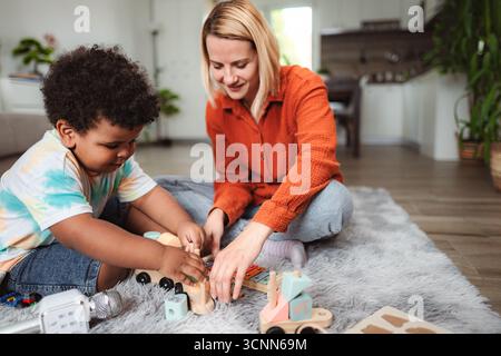Mutter und Sohn spielen mit lehrreichen Spielzeugen auf dem Teppich Stockfoto