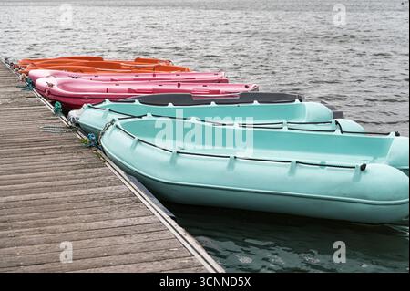 Eine lebendige Auswahl an farbenfrohen Booten liegt sicher am Yachthafen an, wodurch eine malerische Szene entlang der Uferpromenade entsteht Stockfoto