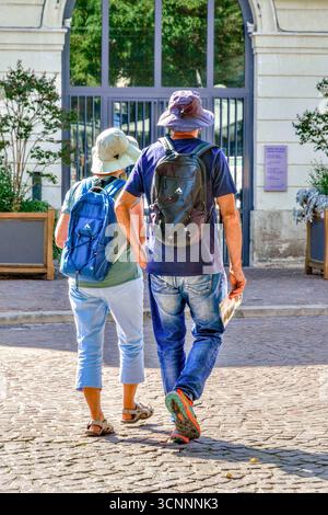 Touristen-Paar in lässiger Kleidung schlendern durch die Altstadt mit McKinley Faro 15 Rucksäcken - Chinon, Indre-et-Loire (37), Frankreich. Stockfoto