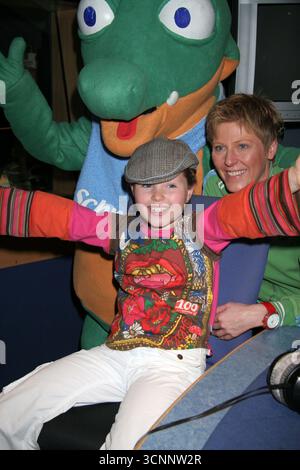 Der neunjährige deutsche Popstar Joy Gruttman posiert mit dem Babykrokodil Schnappi, um die Veröffentlichung der Debütalbons Schnappi am 5. September zu promoten, begleitet von Tante Iris, die das Lied auf Wunsch von Joy schrieb und es im Internet für Familie und Freunde veröffentlichte. Das Lied wurde später von lokalen Radiosendern aufgenommen, was zu einem Plattenvertrag führte. Seitdem hat die Single in Europa mehr als 1 Mio. Exemplare verkauft, in neun Ländern die Spitze der Charts erreicht und in Deutschland den Dreifachplatinstatus erhalten. Das Fotogespräch fand am 24. August 2005 in den Capital Disney Studios in London statt Stockfoto
