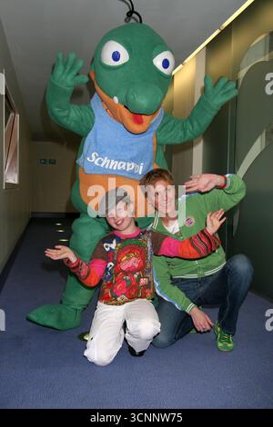 Der neunjährige deutsche Popstar Joy Gruttman posiert mit dem Babykrokodil Schnappi, um die Veröffentlichung der Debütalbons Schnappi am 5. September zu promoten, begleitet von Tante Iris, die das Lied auf Wunsch von Joy schrieb und es im Internet für Familie und Freunde veröffentlichte. Das Lied wurde später von lokalen Radiosendern aufgenommen, was zu einem Plattenvertrag führte. Seitdem hat die Single in Europa mehr als 1 Mio. Exemplare verkauft, in neun Ländern die Spitze der Charts erreicht und in Deutschland den Dreifachplatinstatus erhalten. Das Fotogespräch fand am 24. August 2005 in den Capital Disney Studios in London statt Stockfoto