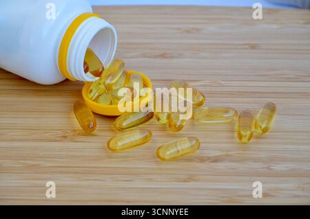 Fischöl Kapseln auf einem Holztisch mit einer Flasche Öl. Stockfoto