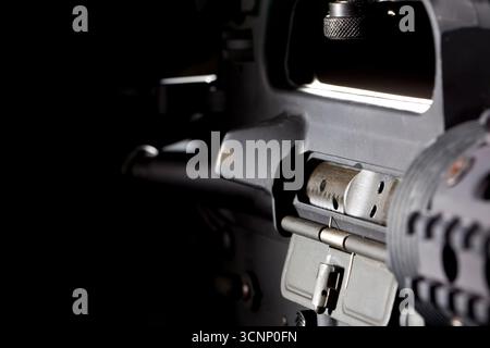 Ein AR-15-Gewehr wird in scharfen Details aufgenommen und in einem Studio vor tiefschwarzem Hintergrund fotografiert, dessen schlanke Linien und Metallic-Oberfläche hervorgehoben sind Stockfoto