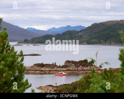 Blick von oben über Plockton über Loch Kishorn in den westlichen schottischen Highlands, während Callums Seehundboot vorbeifährt Stockfoto