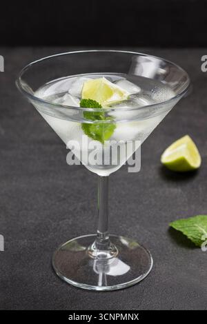 Nebeliges Weinglas mit Limette, Minze und Eis. Schwarzer Hintergrund. Draufsicht Stockfoto