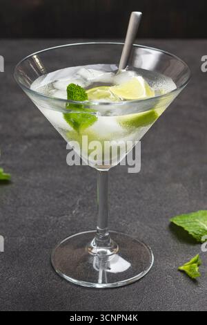 Nebeliges Weinglas mit Limette und Eis. Minzzweige auf dem Tisch. Schwarzer Hintergrund. Draufsicht Stockfoto