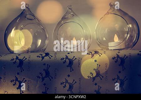 Festliche Weihnachtsdekoration: Glasschmuck mit LED-Kerzen auf einem in Rentierpapier gewickelten Geschenk für ein warmes, gemütliches Ambiente. Stockfoto