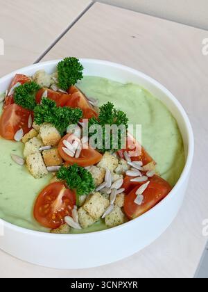 Gesunde cremige grüne Suppe in einer rustikalen Schüssel, perfekt gestylt für eine Nahaufnahme von oben nach unten. Die glatte, samtige Textur der Suppe Stockfoto