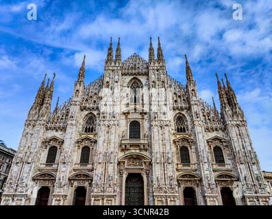 Vorderansicht der gotischen Fassade des Mailänder Doms mit blauem Himmel Stockfoto