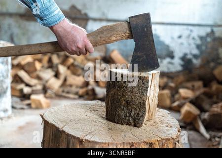 Deutschland - 21. September 2025: Ein Mann spaltet ein Stück Holz mit einer Axt. Das Bild repräsentiert Brennholz, Winterversorgung und traditionelle Energieversorgung durch Holz, das als nachhaltige Wärmequelle für den Winter genutzt wird. *** Ein Mann spaltet mit einer Axt ein Holzstück. Das Bild steht für Brennholz, Wintervorrat und traditionelle Energieversorgung durch Holz, das als nachhaltige Wärmequelle für den Winter genutzt wird. Stockfoto