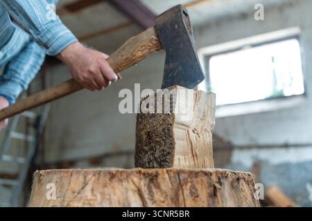 Deutschland - 21. September 2025: Ein Mann spaltet ein Stück Holz mit einer Axt. Das Bild repräsentiert Brennholz, Winterversorgung und traditionelle Energieversorgung durch Holz, das als nachhaltige Wärmequelle für den Winter genutzt wird. *** Ein Mann spaltet mit einer Axt ein Holzstück. Das Bild steht für Brennholz, Wintervorrat und traditionelle Energieversorgung durch Holz, das als nachhaltige Wärmequelle für den Winter genutzt wird. Stockfoto