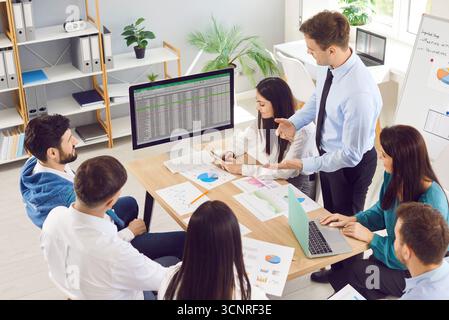 Business-Team teilt sich im Büro einen Laptop, sieht sich die Präsentation der Buchhaltung von Startup-Unternehmen an, sieht das Finanzprojekt an Stockfoto