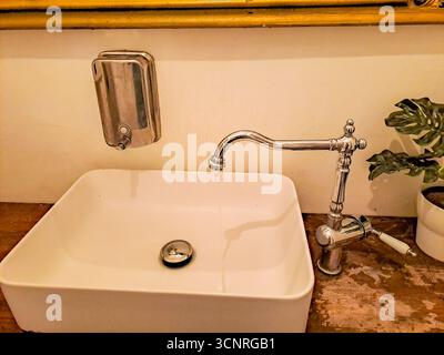 Wasserhahn in Vintage-Silber mit fließendem Wasser mit Waschbecken und Seifenspender. Hochwertige Fotos Stockfoto
