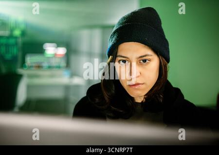 Weiblicher junger Hacker, der am Computer im Dunkelraum-Programmiercode arbeitet Stockfoto