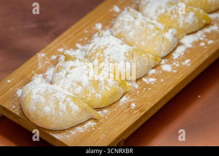 Rohe und gekochte japanische Gyoza-Knödel auf rustikalen Oberflächen – handgemachte asiatische Küche Stockfoto