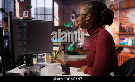 Silicon Valley Venture Programmierer löst Aufgaben mit KI LLM Chatbot unter Verwendung von Predictive-Technologie. afroamerikanischer IT-Startup-Mitarbeiter, der PC verwendet, um mit dem generativen Modell, Kamera B, zu interagieren Stockfoto