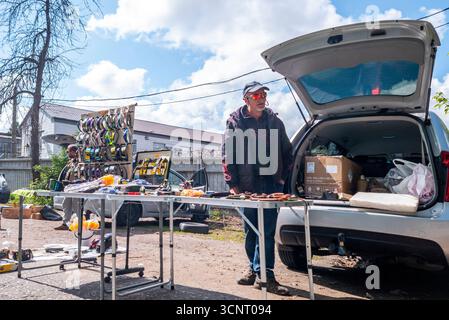 Kiew, Ukraine 11. Mai 2025, Straßenverkäufer auf einem Flohmarkt im Freien mit verschiedenen Werkzeugen, Zubehör und Haushaltsgegenständen auf Tischen und Regalen, die an einem sonnigen Tag direkt aus einem Kofferraum verkauft werden Stockfoto