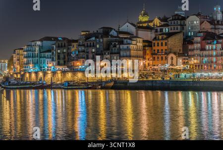 Farbenfrohe Häuser am Fluss, beleuchtet bei Nacht mit lebhaften Reflexen auf ruhigem Wasser im historischen europäischen Stadtbild Stockfoto